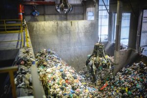 High angle view of large indoor waste management facility and mechanical grabber in use transferring potential recyclables.